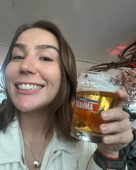 Renata sorrindo com um chope na mão num happy hour de sexta